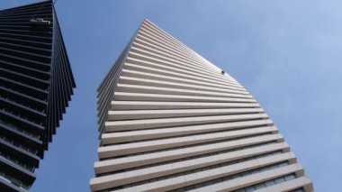 Bir temizlik şirketinin çalışanı gökdelenlerde mavi gökyüzüne karşı çalışıyor. Yan yana bulunan iki yüksek katlı ofis binasının güzel geometrik şekli. Modern gökdelen.