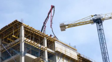 İşçiler şehir merkezinde yeni bir yerleşim yerinin inşaat sahasına beton döküyorlar..