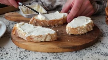 Erkek bir şef mutfakta krem peynirli bruschetta hazırlar. Sebzelerin arka planında güzel bir ahşap kesim tahtasında.