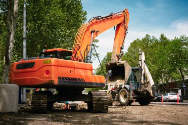Şehirdeki su ve kanalizasyon sisteminin yerini kamu hizmetleri işçileri alıyor. Yoldaki kazıcıda çalışıyor..
