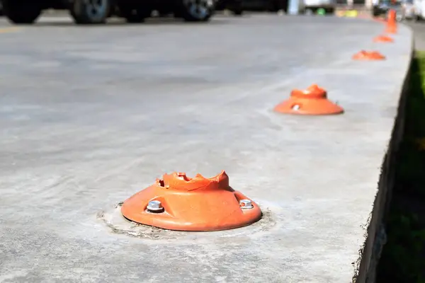 Close-up of broken plastic orange barrier bollards in a parking lot.