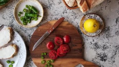 Krem peynirli bruschetta yapmak için kirazlı domates ve yeşil biber. Sebzelerin arka planında güzel bir ahşap kesim tahtasında.