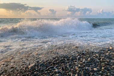 Deniz kıyısında gün batımına karşı bulutlu güzel dalgalar..