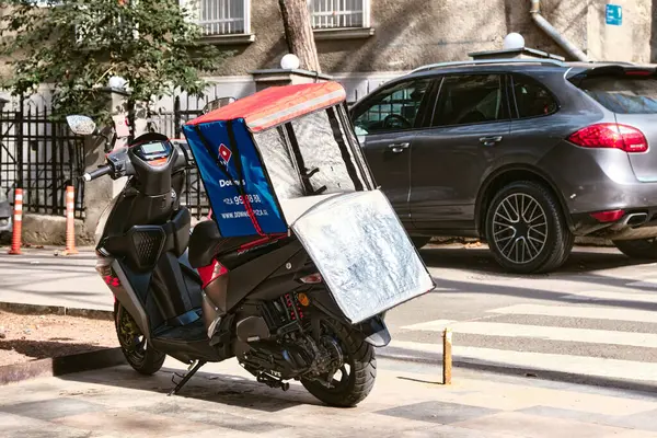 An empty motorcycle with a food delivery box on the street in city: Tbilisi, Georgia, February 19, 2023.