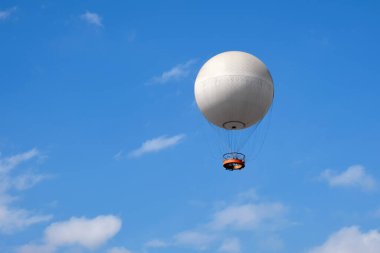 Turistlerle dolu yürüyen bir balon bulutlu mavi gökyüzünün arka planında uçuyor..