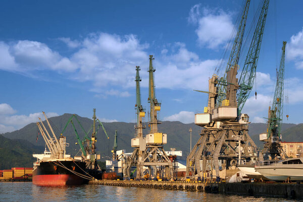 Грузовой корабль разгружается в морском порту. Дешевые перевозки и доставка товаров по всей планете.