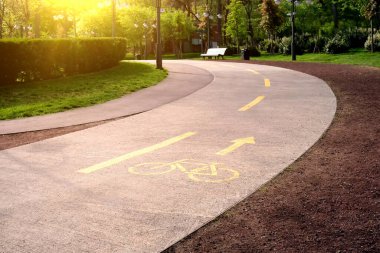 Şehir parkında sarı boya yolu ile işaretlenmiş. Ağaçların ve bankların arkasında.