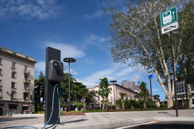 Şehirdeki elektrikli araçları gökyüzüne karşı şarj etmek için bir istasyona yakın çekim.