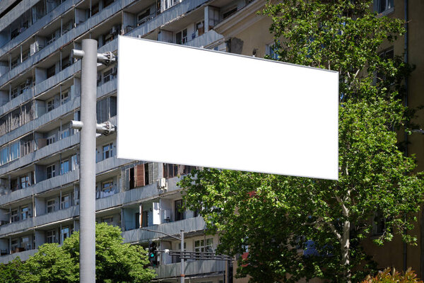 Big stand billboard on the street in the city among green trees. Template for design.