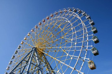 Temiz gökyüzünün arka planında geniş bir dönme dolabın alt görüntüsü.