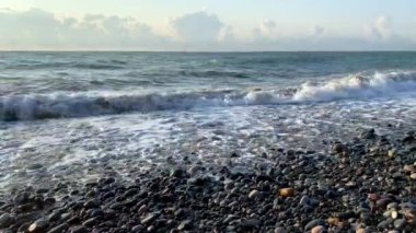 Deniz kıyısında güzel bir gün batımı. Büyük dalgalar kayalık kıyıya çarpıyor..