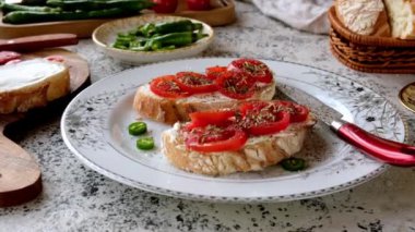 Krem peynirli taze vişneli bruschetta. Sebze arkaplanına karşı kocaman beyaz bir tabakta.