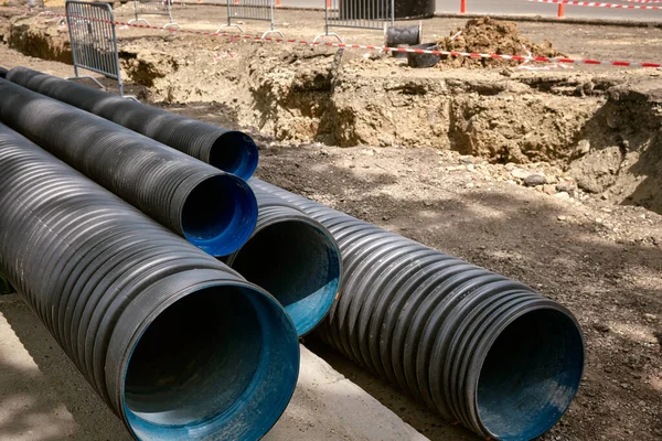 Large plastic corrugated pipes for water supply lie on the street in the city. The work of utilities to improve the infrastructure of the metropolis.