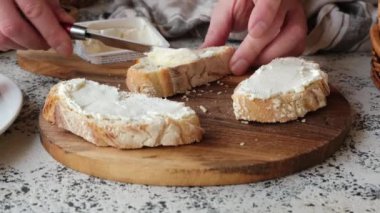 Erkek bir şef mutfakta krem peynirli bruschetta hazırlıyor. Sebzelerin arka planında güzel bir ahşap kesim tahtasında.