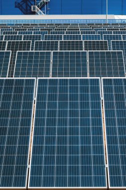 Bir girişimin arka planına karşı elektrik üretimi için pek çok endüstriyel güneş panelinin dikey görüntüsü.