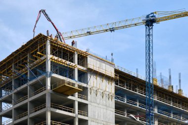 Yeni bir modern konut kompleksi inşaatı. İşçiler yeni bir beton yığınının çatısında bekliyor..