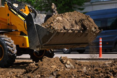 Şehrin caddesindeki kazıcı kovasına yakın çekim. Metropolün altyapısını iyileştirmek için yapılan hizmetler.