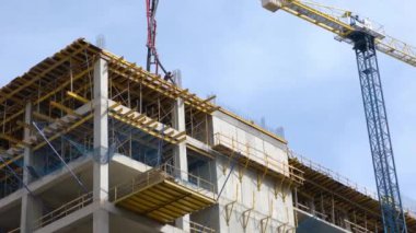 Yeni bir modern konut kompleksinin yakın plan inşaatı. İşçiler beton döker.