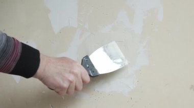 Çatlak beyaz duvarı spatulayla tamir eden bir adam. Duvarların ve açıkların onarımı.