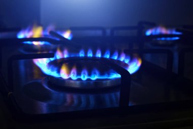 Gaz, mutfak sobasının ocağında yanıyor. Mutfak ocağı karanlıkta yanıyor, yakın plan.. 