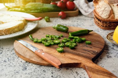 Krem peynirli bruschetta yapmak için dilimlenmiş yeşil biber. Sebzelerin arka planında güzel bir ahşap kesim tahtasında.