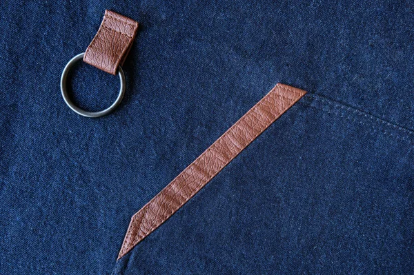 Close-up of dark blue cotton fabric with beige leather inserts. Design elements in clothes.