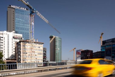 İstanbul, Türkiye - 21 Ekim 2023 'te İstanbul, Türkiye' de bir yolcu taksisi hızla kentte gökdelenlerin arka planına ve yeni binaların inşasına doğru ilerliyor.
