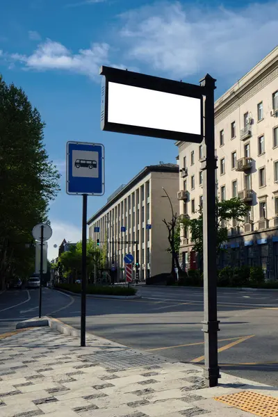 Vertical image of an empty information sign at a bus stop against the backdrop of the city. Template for design.