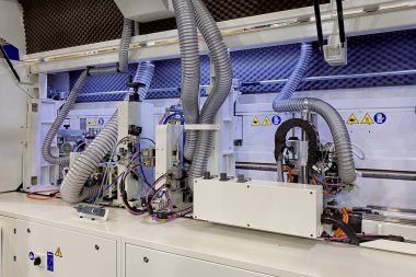 Mobilya üretimi için endüstriyel ekipmanlara yakın çekim. Tahta panele bant yapıştırmak için otomatik makine.