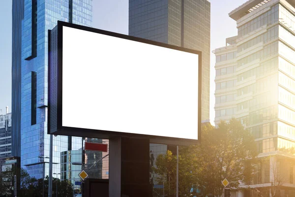 A large information display for advertising on the street in the city, against the backdrop of a skyscraper and a beautiful sunset sky.