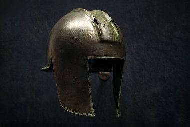 Yunan savaşçısının karanlık bir arka planda süslemelerle süslenmiş antika demir miğferi. Antik Sanat Sergisi: İstanbul, Türkiye - 19 Ekim 2023.