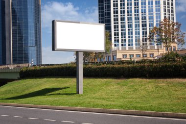 Kentteki yüksek binaların arka planına karşı caddenin yakınına büyük bir açık hava reklamı sergileniyor..