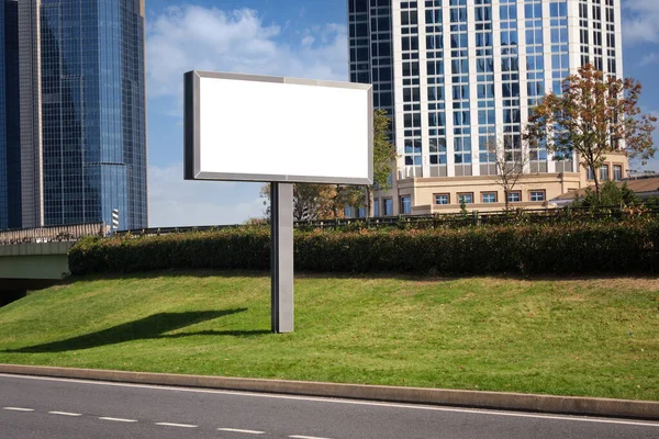 A large information display for outdoor advertising is installed on the street near the road against the backdrop of high-rise buildings in the city.