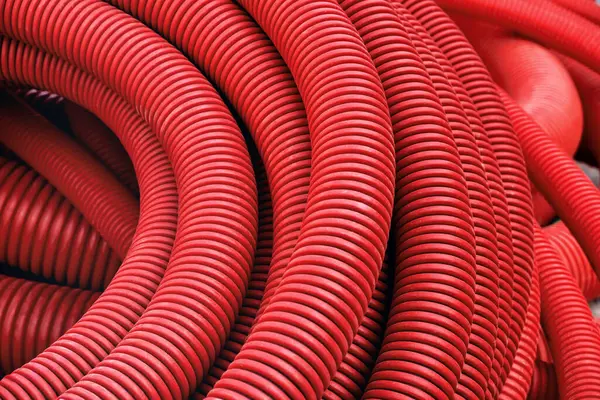 Red plastic corrugated pipe for installation of communications and electrical cables. Modern construction technologies.