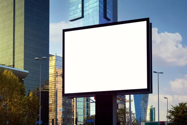 A large information display for advertising on the street in the city, against the backdrop of a skyscraper and a beautiful sky.