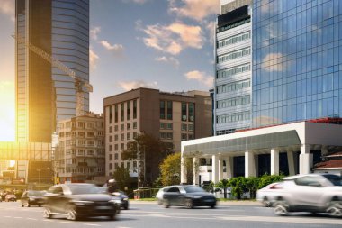 Şehrin prestijli bir bölgesinde arabalar hızla gökdelenlerin arka planına doğru ilerliyorlar. Bulanık hareket.