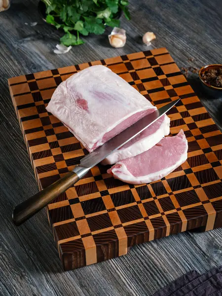 大块切碎的猪肉放在一块漂亮的木板上 在家里的厨房里放着蔬菜和香料 自制食品烹调概念 图库图片