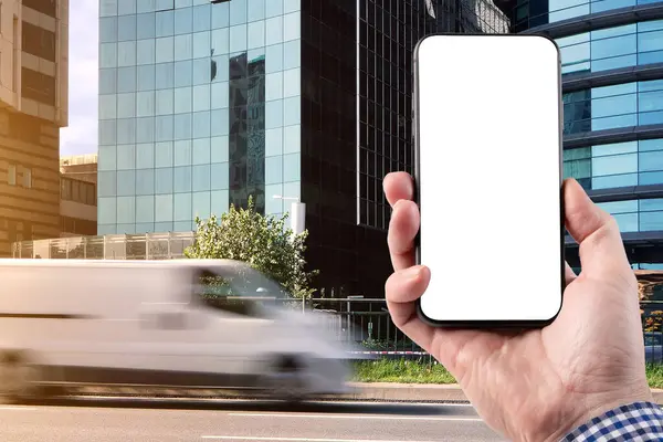 一个男人手里拿着一部智能手机 背景是一辆装有送货服务车的汽车在路上疾驰而过 模糊的动议 图库图片