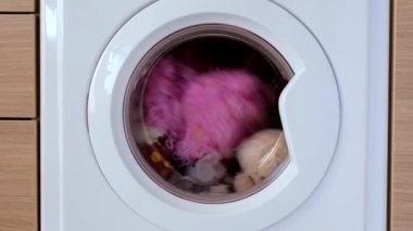 Beyaz bir çamaşır makinesi kirli çocukların oyuncaklarını yıkar. Yıkanmak için yumuşak oyuncaklar, yakın çekim..