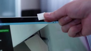 Bilgisayardaki webcam 'i bant ile izleyen bir adamın yakın çekimi. Siber güvenlik kavramı ve kişisel verilerin kaydedilmesi.