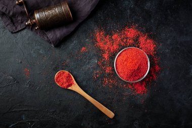 Üst tarafta küçük bir kase kırmızı biber, tahta kaşık ve arka planda el değirmeni. Kafe ve restoran menülerinin dizaynı için arka plan.