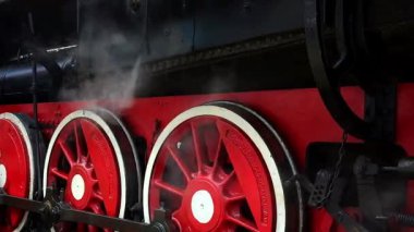 Tren istasyonundaki buharlı lokomotif tekerleklerinin yan görüntüsü. Trenin arka planına karşı buhar esintisi. Çalışan tren müzesi.