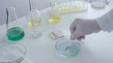 Kimya laboratuvarındaki bir bilim adamı petri kabındaki sıvının asit bazlı dengesini ölçüyor. Konsept: araştırma, biyokimya, ilaç.
