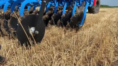 Araziyi işlemek için geniş, modern bir saban mavisi ya da disk harrow 'un yakın çekimi. Panoramik hareket kamerası. Tarımsal ekipman çalışmalarına hazırlık.