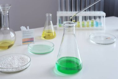 Laboratuvar pipetinin, araştırma laboratuarındaki özel bir reaktörü şişeye boşalttığı yakın plan. Konsept: araştırma, biyokimya, ilaç ve bilim.