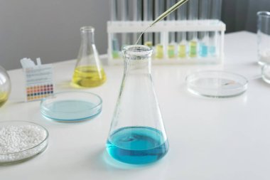 Laboratuvarda bir bilim adamı renkli bir sıvıyı test tüplerinde analiz etmek için pipet kullanır. Konsept: araştırma, biyokimya, doğa, ilaç.