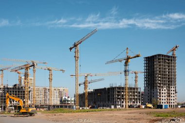 Yeni bir konut kompleksi inşaatı. Birçok yüksek binalı vinç ve endüstriyel inşaat ekipmanı bir inşaat binasının arka planına karşı.