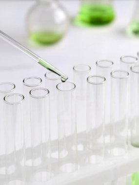 Dikey görüntü. Laboratuvarda bir bilim adamı renkli bir sıvıyı test tüplerinde analiz etmek için pipet kullanır. Konsept: araştırma, biyokimya, doğa, ilaç.