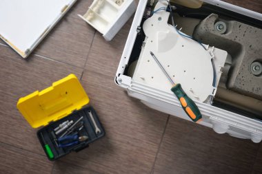 Parçalanmış bir çamaşır makinesinin üzerinde duran tornavidanın en üst görüntüsü. Ev aletlerinin profesyonel onarımı. Seçici odak