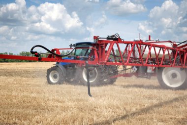 Tarlalara gübre ya da su püskürtmek için karavan tarım ekipmanı taşıyan bir traktör. Tarımsal ekipman işi.